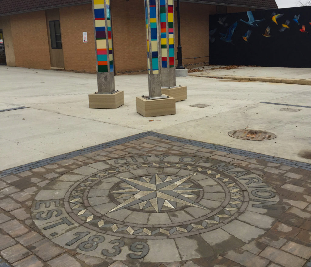 An inlay serves as a celebration of local heritage and a focal point with Marion, Iowa's ImaginArt in the Alleys creative placemaking project, which seeks to transform Uptown Marion's alleyways into welcoming, pedestrian-friendly spaces. This photo, taken Dec. 1, 2016, also includes a portion of the only commissioned mural in the project, "Midnight Wonder" by Argentine-born, American-based artist Cecilia Lueza. Colorful pillars by Indiana-based artists Luke Crawley and Quincy Owens light up the space at night. (Lynda Waddington/The Gazette)