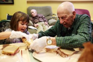 Alex Stafie, 5, and Wallace Scherer, 92, make sack lunches for the homeless during an activity at Providence Mount St. Vincent home for older adults in West Seattle. The seniors and children connect in a variety of programs including art classes, exercise, music time and story time.