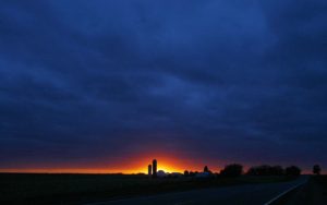 The sun sets over a silhouette of a rural Iowa farm corn silo outside of Rock Rapids, Iowa on November 14, 2007. (Shannon Stapleton/Reuters)