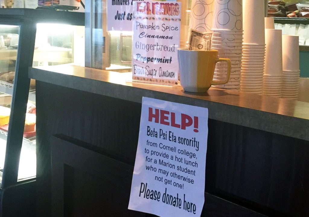 A dollar bill peeks out of a donation cup on the front counter of Mr. Beans, a coffee shop in Marion, Iowa, on Dec. 4, 2017. Members of the Beta Psi Eta sorority at Cornell College in Mount Vernon are collecting money to help students in the Marion Independent School District afford school lunches.
