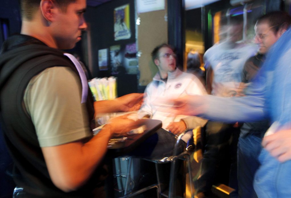21-only - Ryan Lopez checks patron identification as people come through the door at Studio 13 in downtown Iowa City in this 2010 file photo.