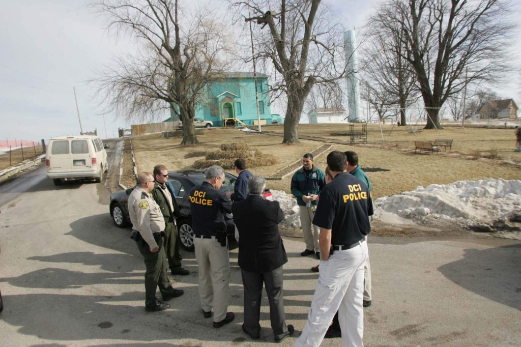 Officials from Muscatine County and the Iowa Division of Criminal Investigation huddle on Feb. 6, 2009 near property used by Henry's Turkey Service in Atalissa to house intellectually disabled workers.
