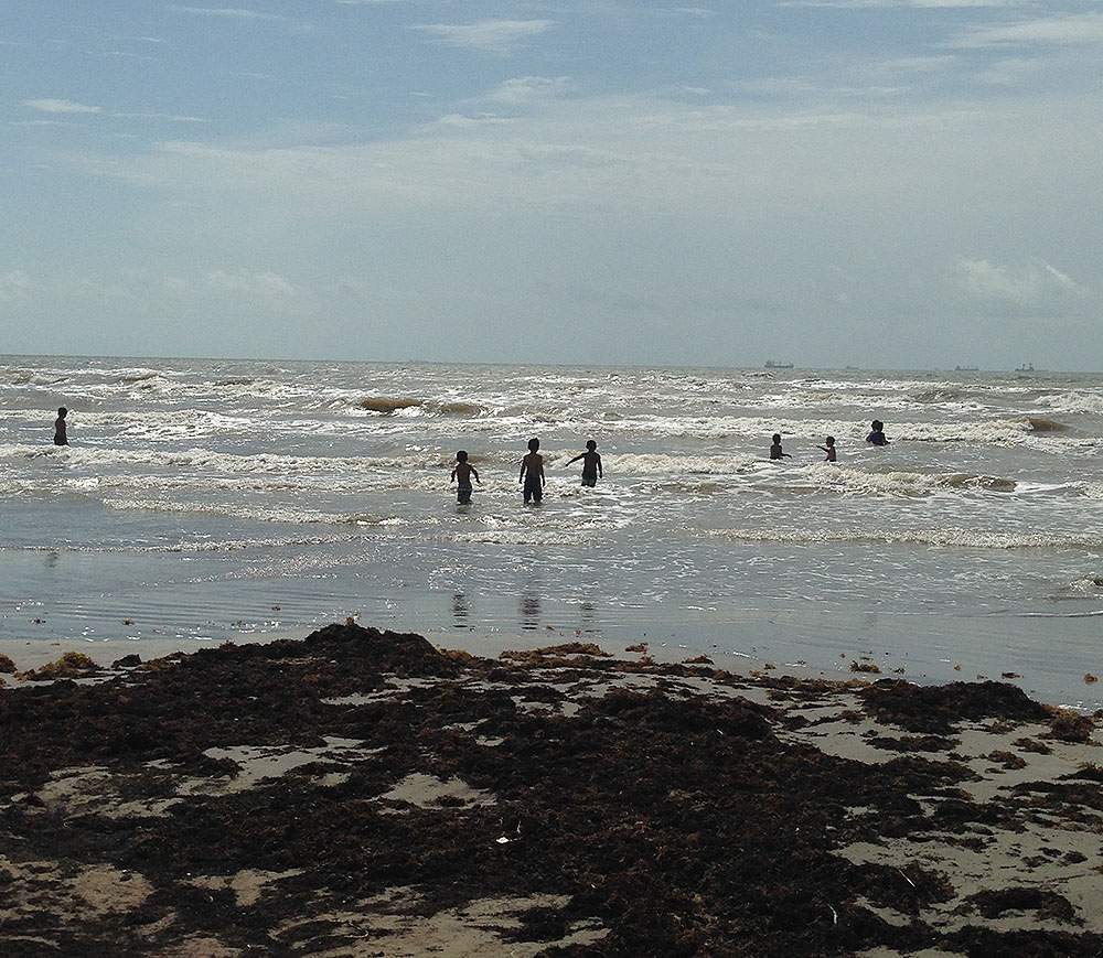 Very few people were brave enough to play in the brown waves on the Galveston Island, Texas shore.